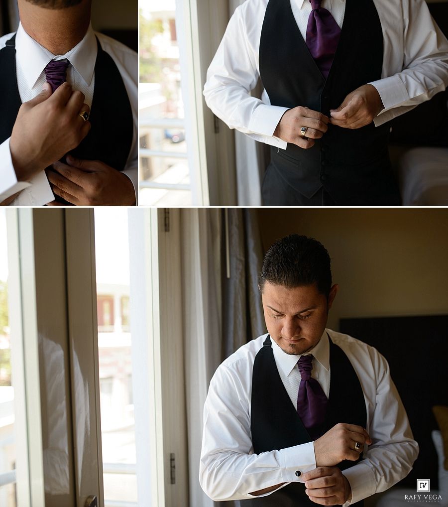 Groom getting dressed in black vest and purple tie, adjusting cufflinks and tie before wedding ceremony.