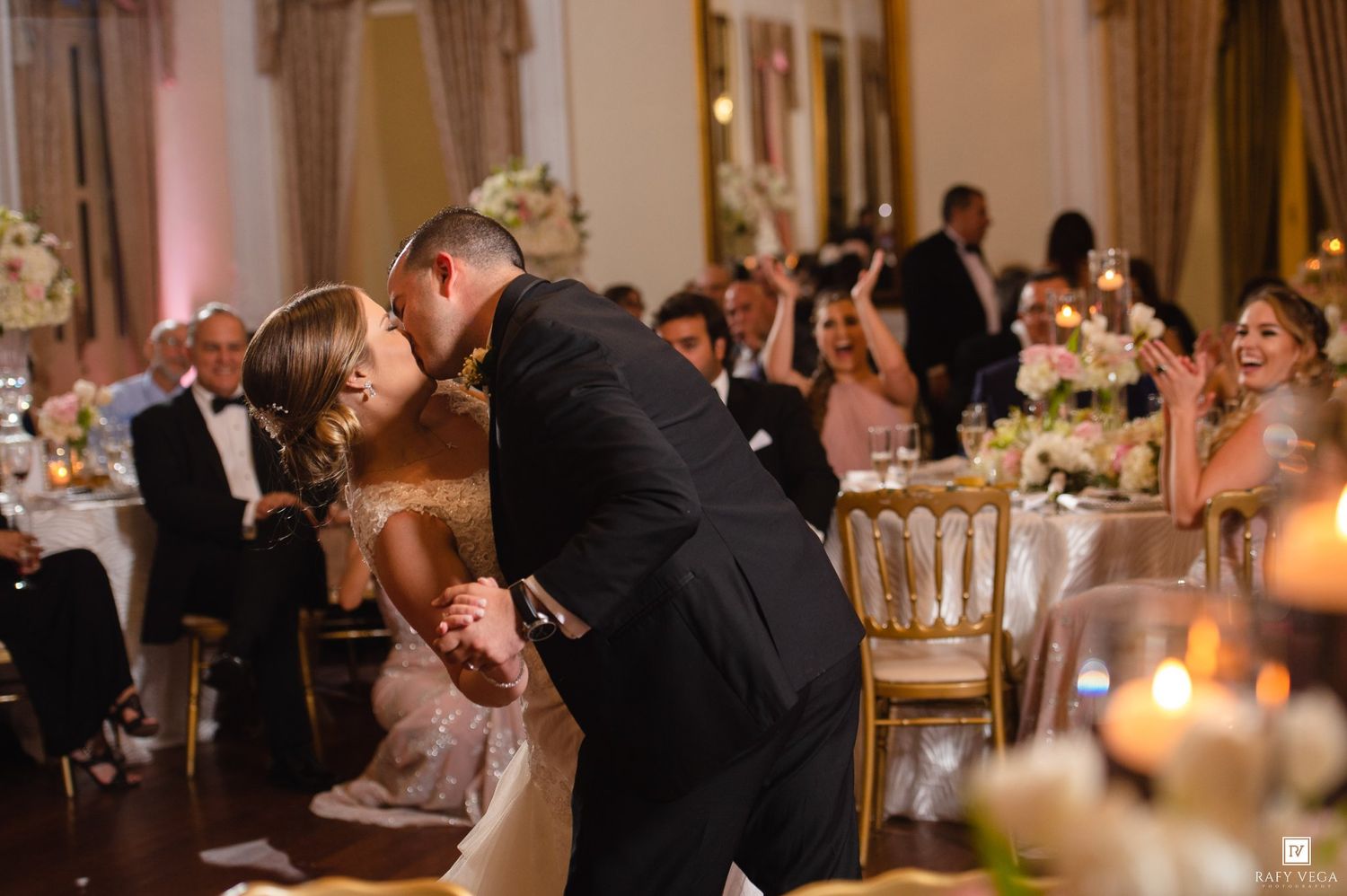 Bride and groom share a romantic dip kiss on the dance floor during their elegant wedding reception.