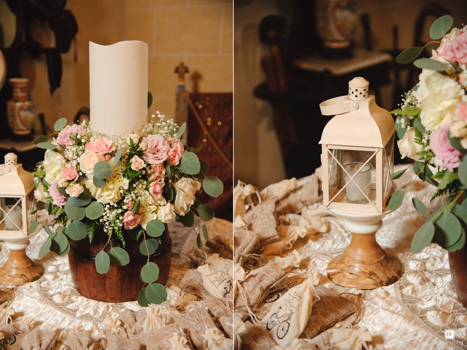 Rustic wedding centerpiece with pink roses, eucalyptus, white candle in wood holder, and lantern on lace tablecloth.