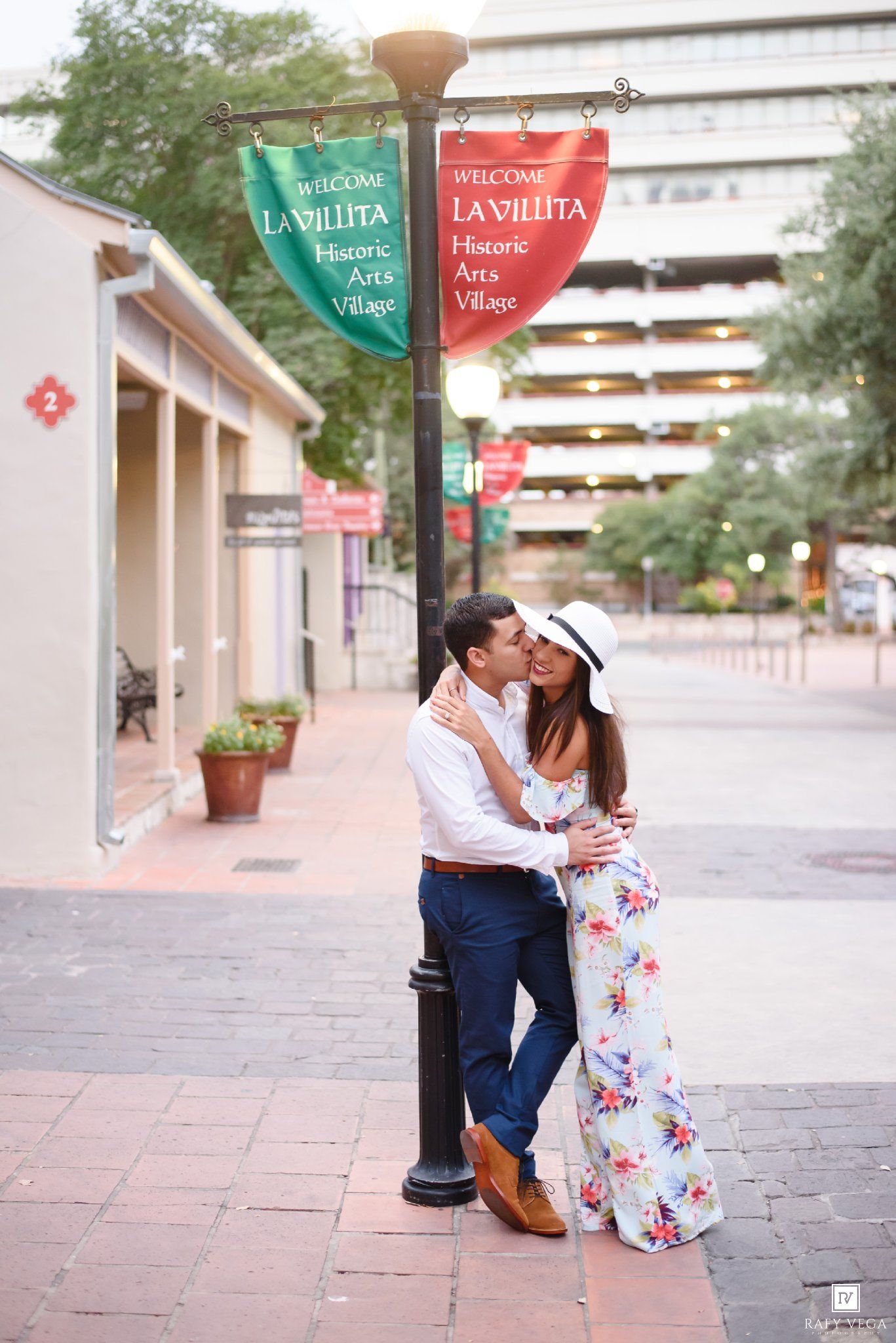 Couple sharing a romantic kiss under La Villita Historic Arts Village banners in San Antonio, TX.