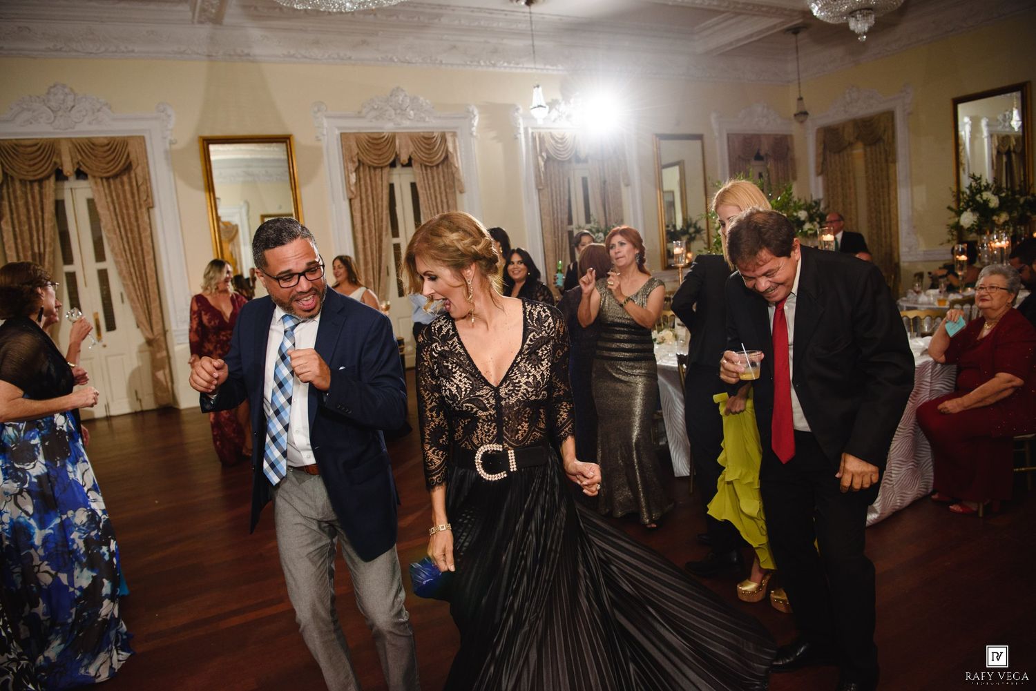 Guests dancing joyfully at an elegant wedding reception in a grand ballroom.
