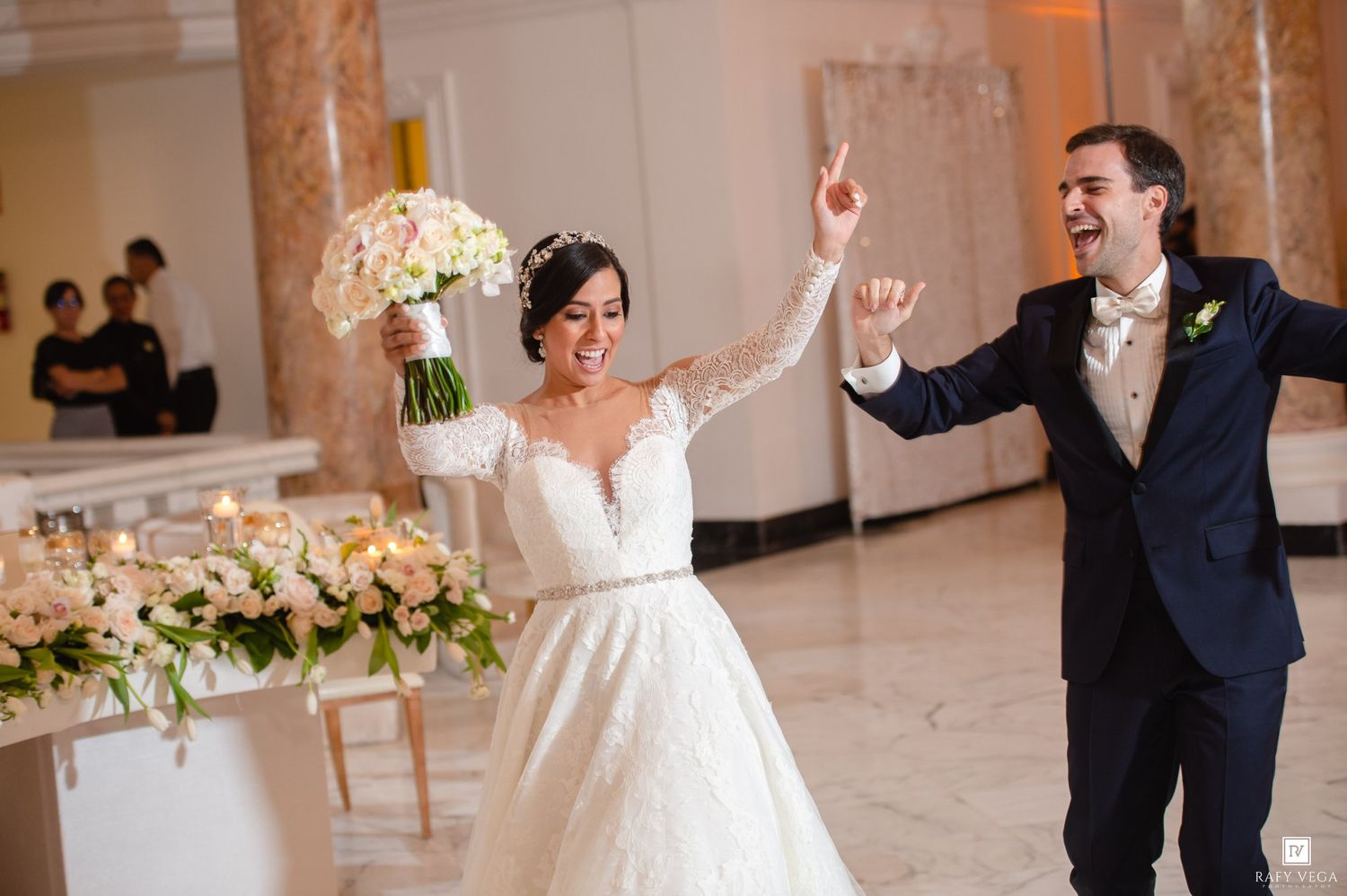 Joyful bride and groom make grand entrance at elegant wedding reception, bride holding bouquet.