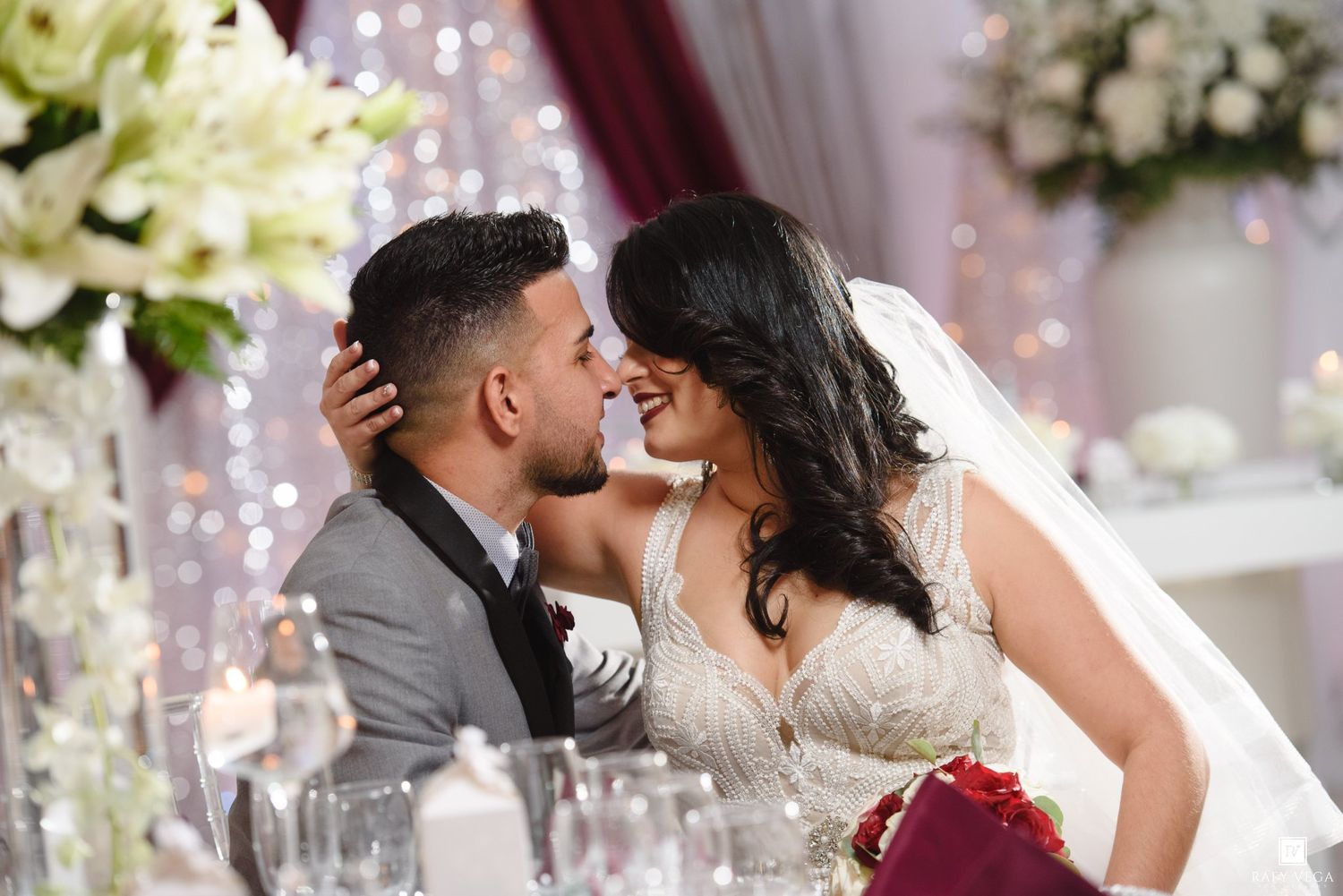 Bride and groom sharing a romantic moment at their wedding reception, surrounded by elegant floral decorations.