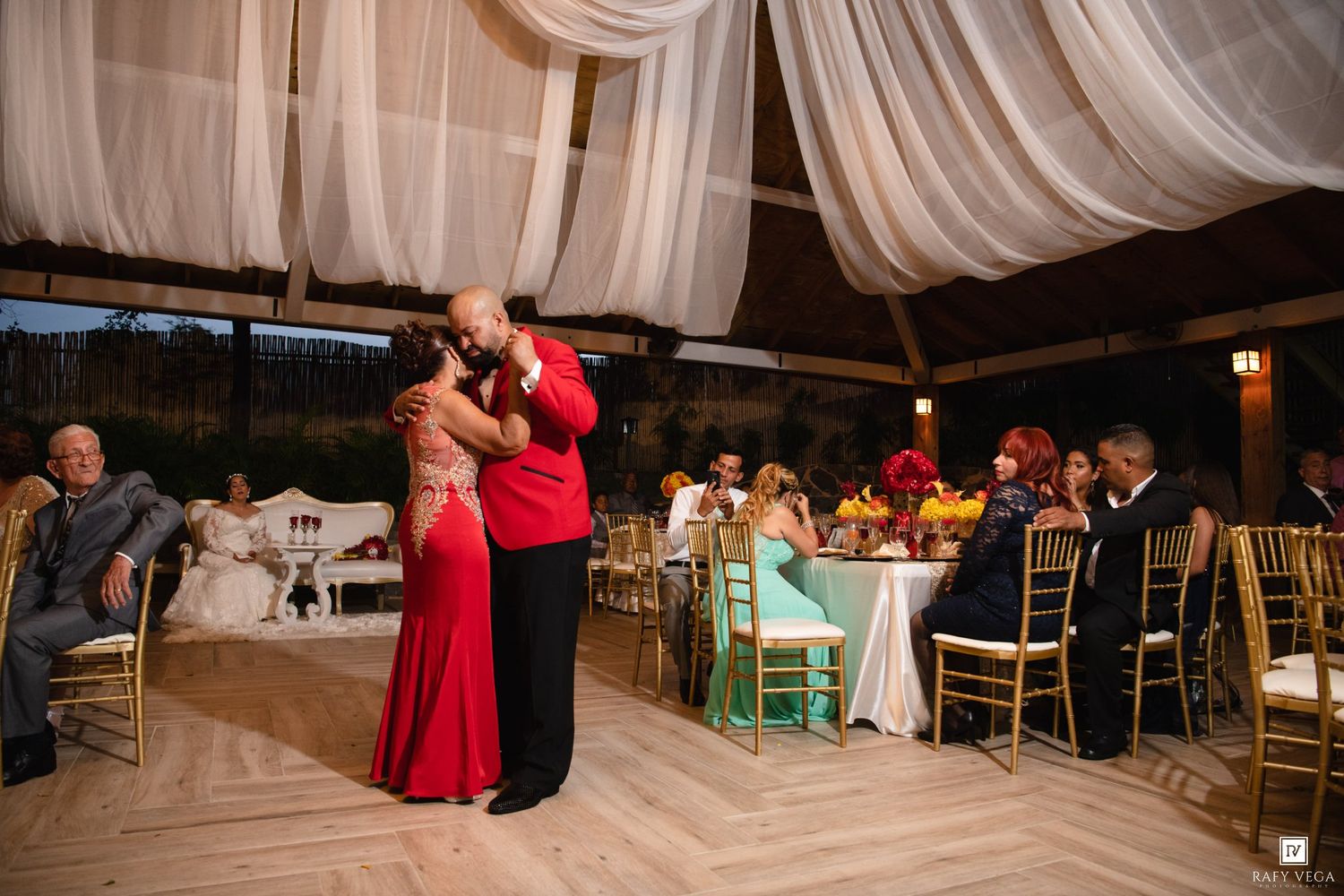 Couple shares romantic dance at elegant wedding reception with draped ceiling decor.