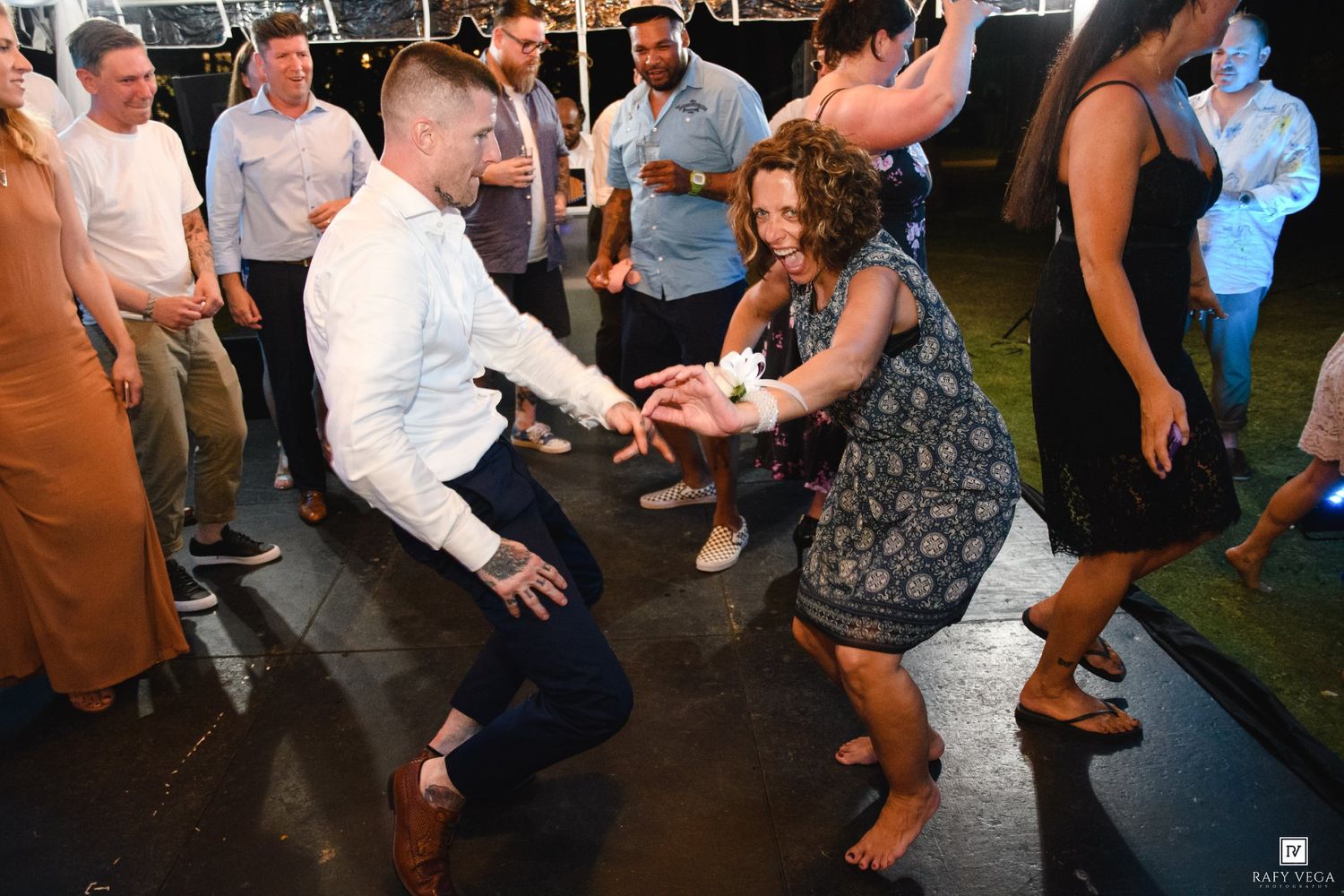 Guests dancing energetically at an outdoor evening wedding reception celebration.