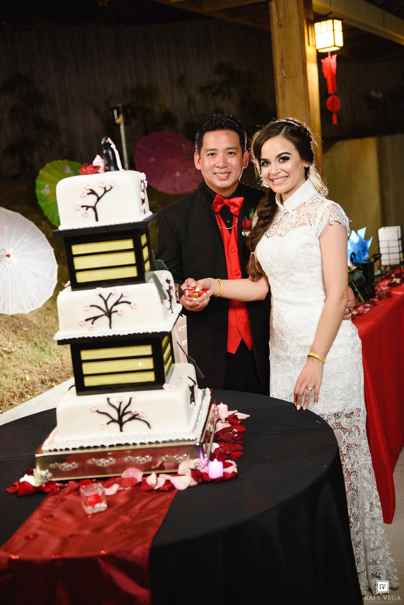 Bride and groom cutting elegant Asian-themed four-tier wedding cake with Japanese lantern design.