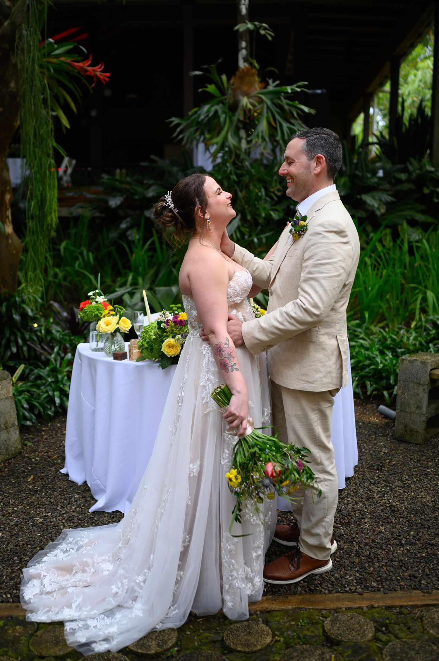 Bride and groom share a joyful moment at their tropical outdoor wedding ceremony, surrounded by lush greenery.