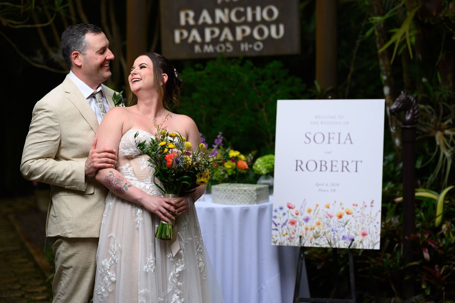 Sofia and Robert smile together at their outdoor wedding at Rancho Papapou, bride holding colorful bouquet.