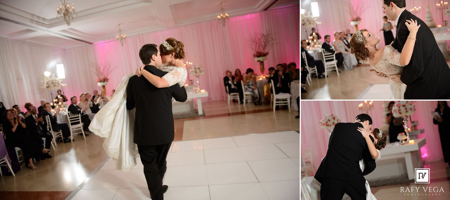Bride and groom share their first dance at an elegant wedding reception with pink lighting and white decor.