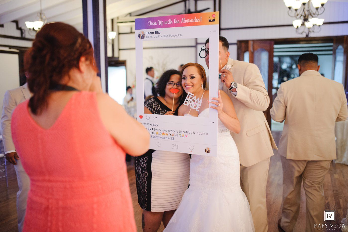 Wedding guests pose with a decorative social media frame prop at a reception venue.