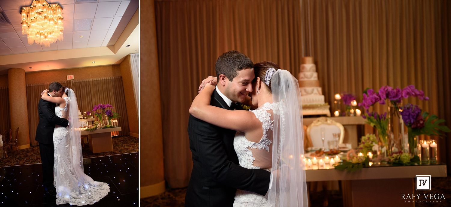 Bride and groom share first dance at elegant wedding reception with floral arrangements and tiered cake.