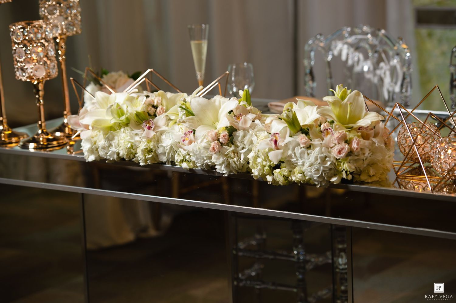 Elegant floral centerpiece with white hydrangeas and roses on a mirrored table at a formal event.