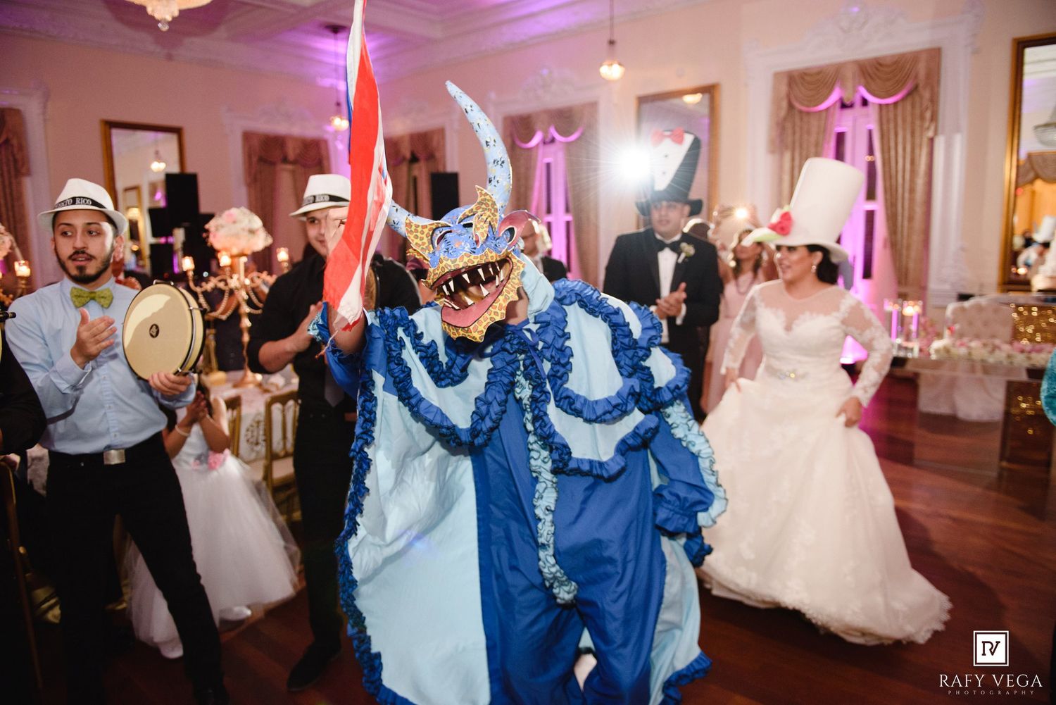 Colorful carnival performer in blue costume entertains wedding guests on dance floor at reception.