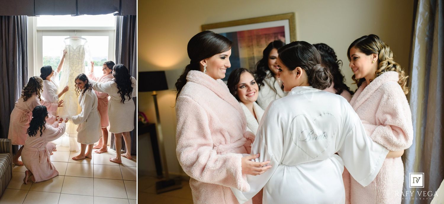 Bridesmaids in white robes and pink fur coats help bride prepare on wedding morning in hotel room.
