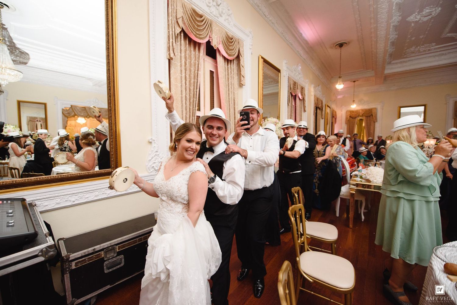 Bride and groom celebrating at elegant wedding reception with guests cheering in decorated ballroom.