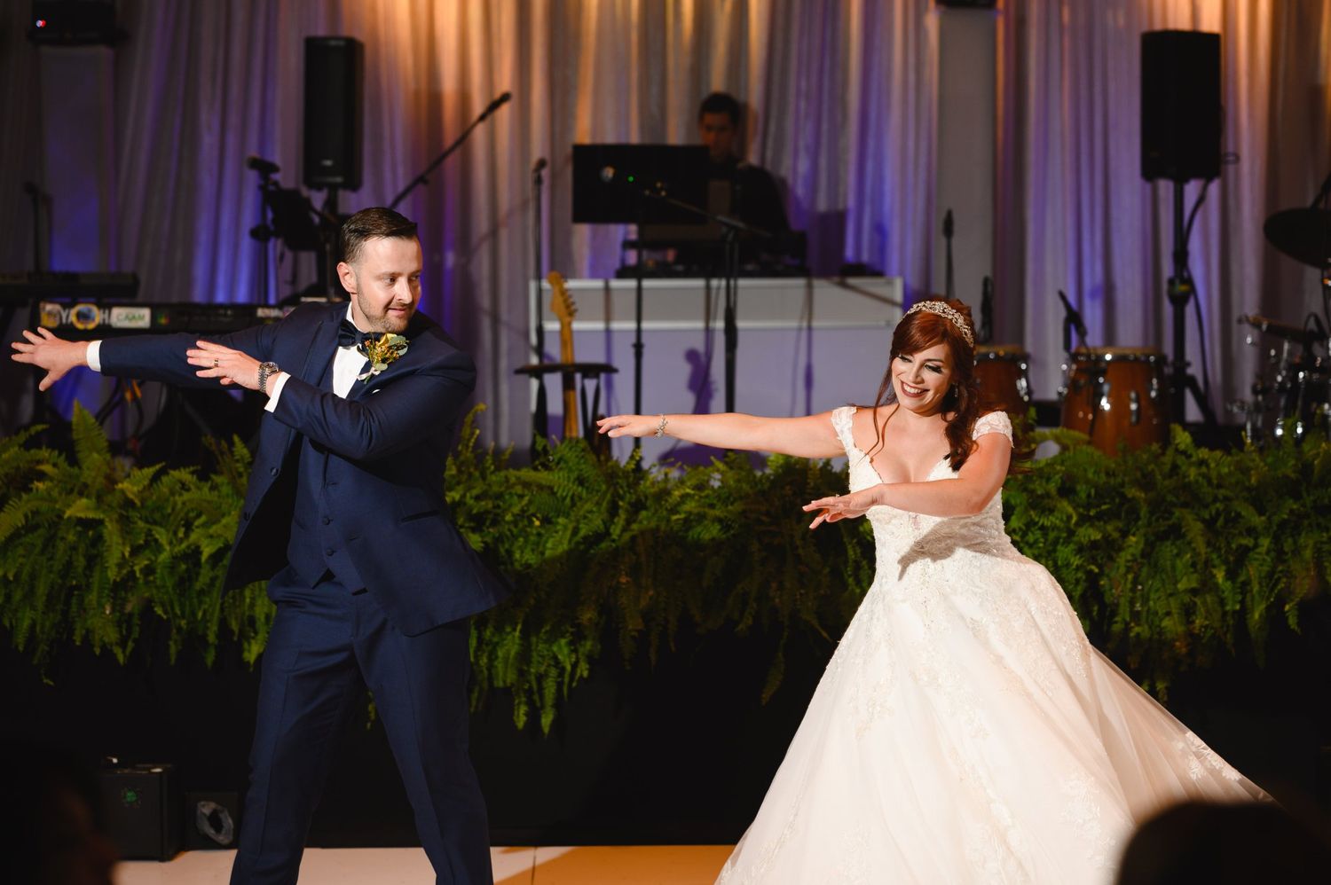 Bride and groom performing a fun choreographed first dance at their wedding reception with a live band.