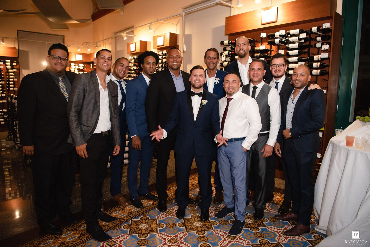 Group of well-dressed men posing together at an elegant wedding reception venue.