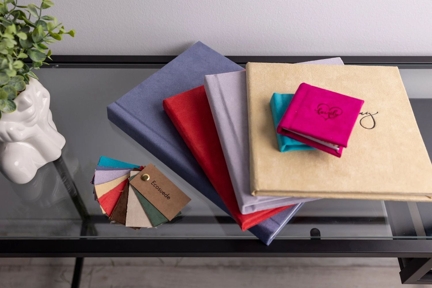 Colorful fabric swatch books and sample binders displayed on a glass table for wedding or event planning.