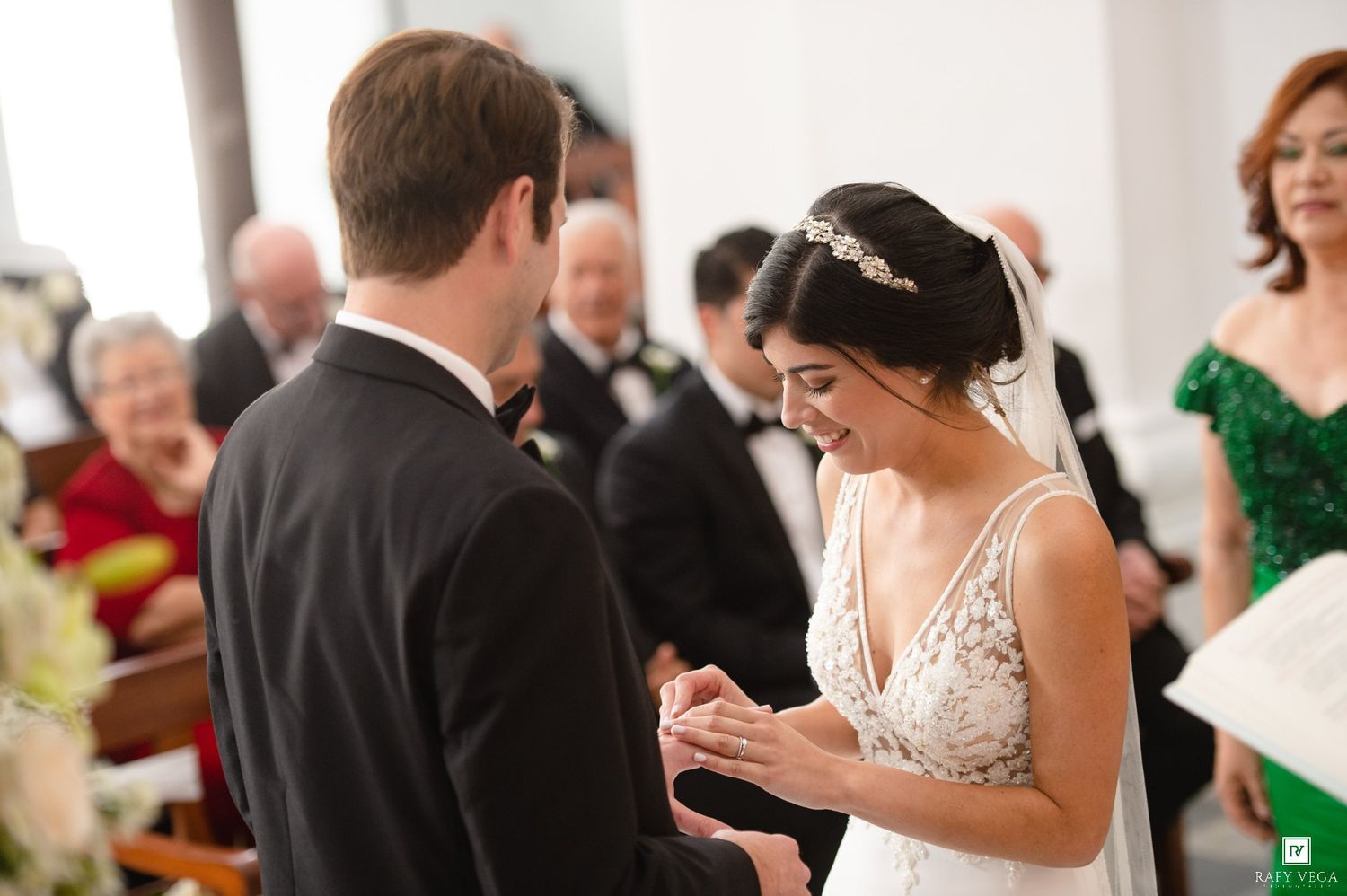 Bride smiling joyfully as groom places wedding ring on her finger during elegant church ceremony.