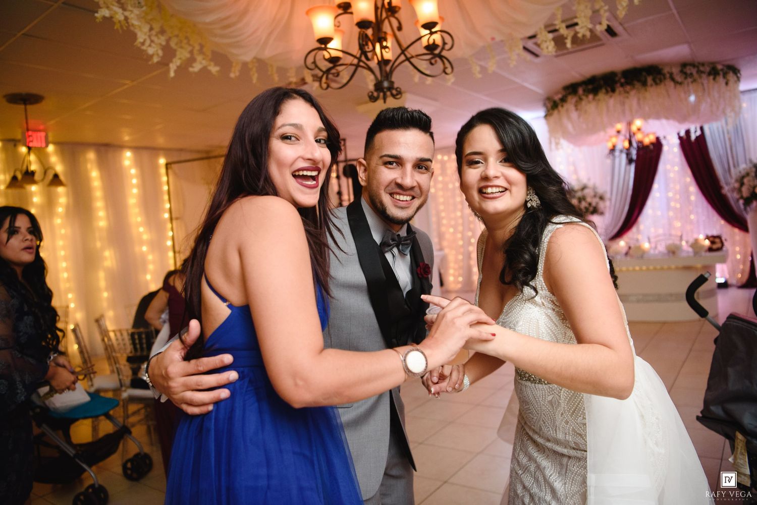 Joyful bride, groom, and bridesmaid celebrating together on the wedding reception dance floor.