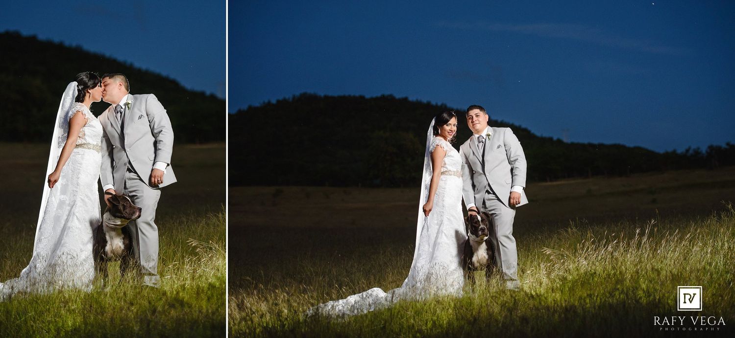 Bride and groom share a romantic kiss in a green meadow under a dramatic night sky in a stunning outdoor wedding photo.