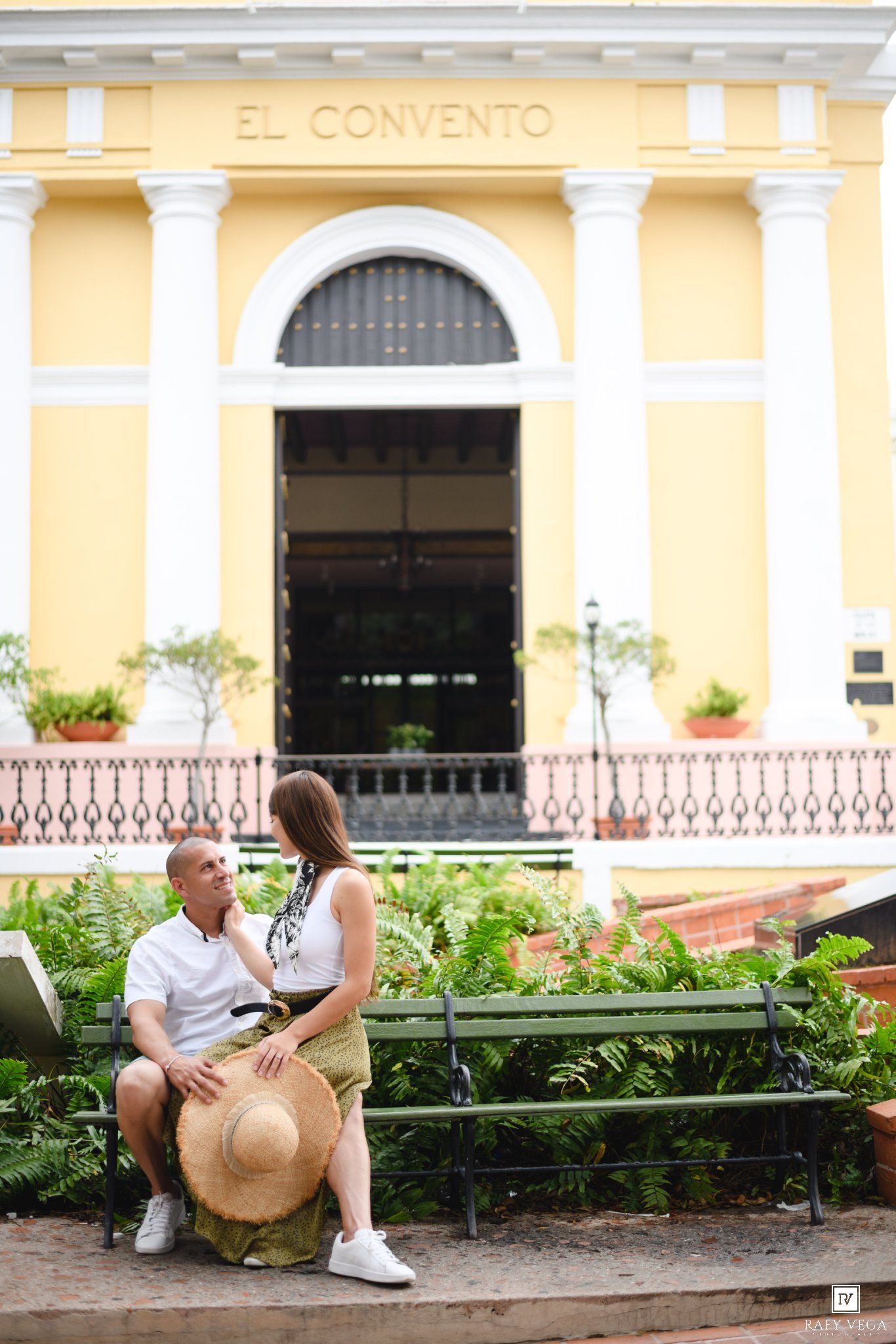 Couple sitting on a bench in front of El Convento hotel in Old San Juan, Puerto Rico.
