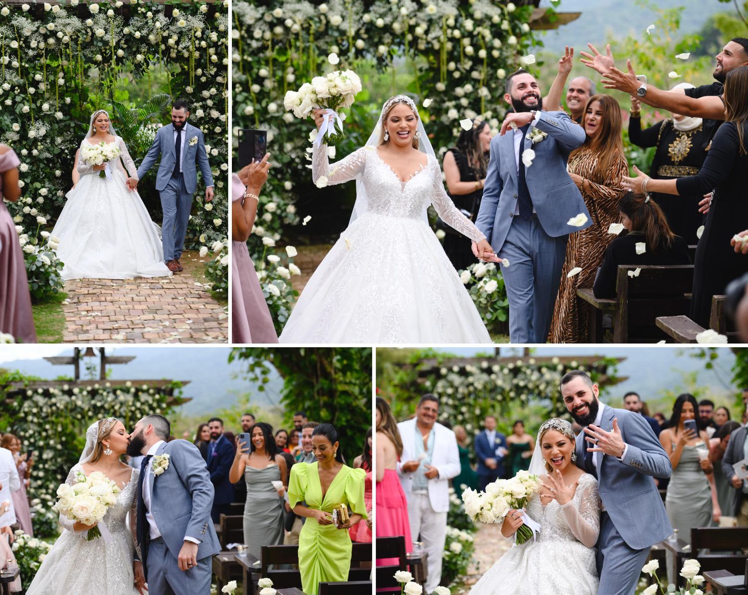 Bride and groom walk down outdoor wedding aisle surrounded by floral arch and cheering guests throwing petals.