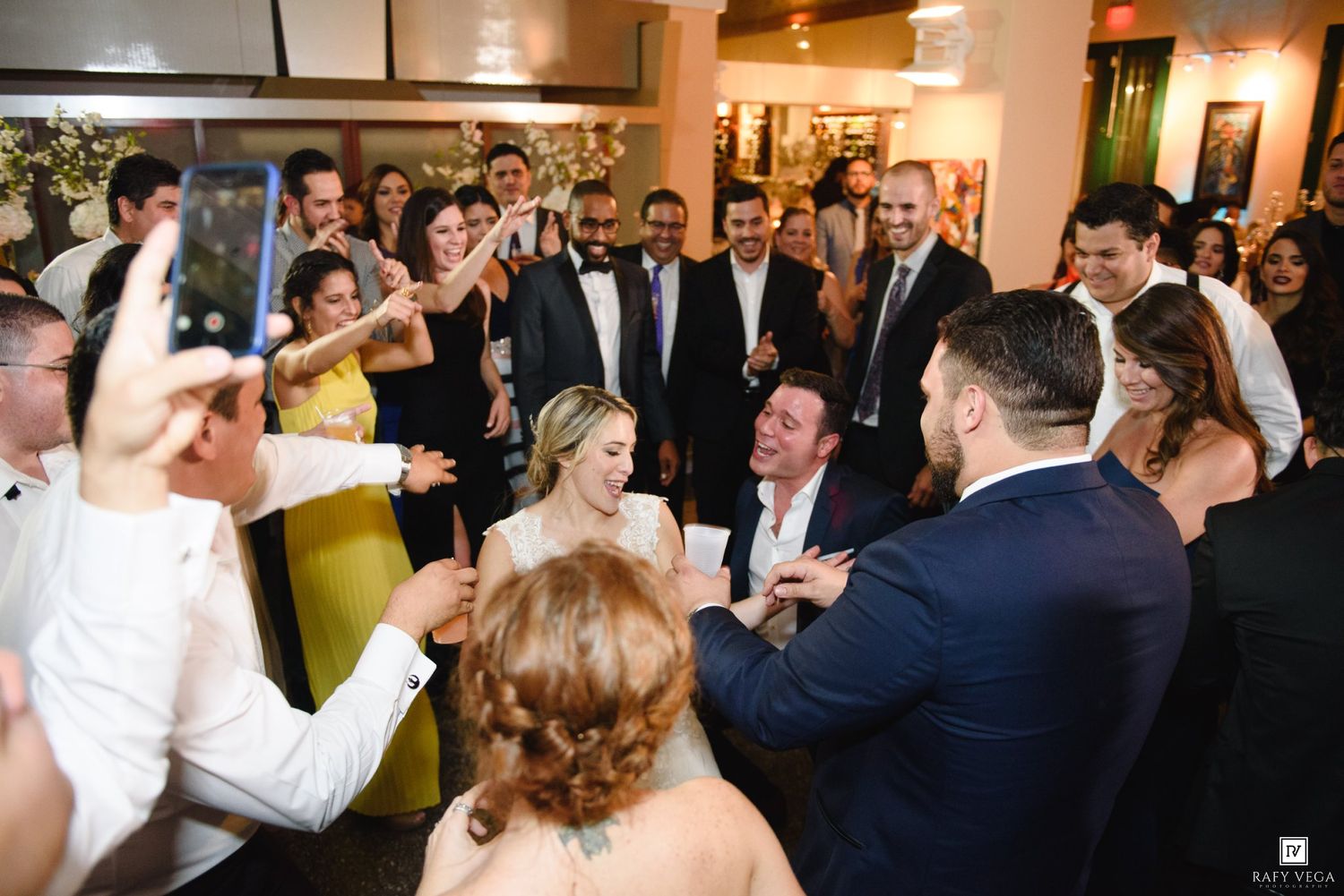 Bride and groom share a joyful moment on the dance floor surrounded by cheering wedding guests at a elegant reception.