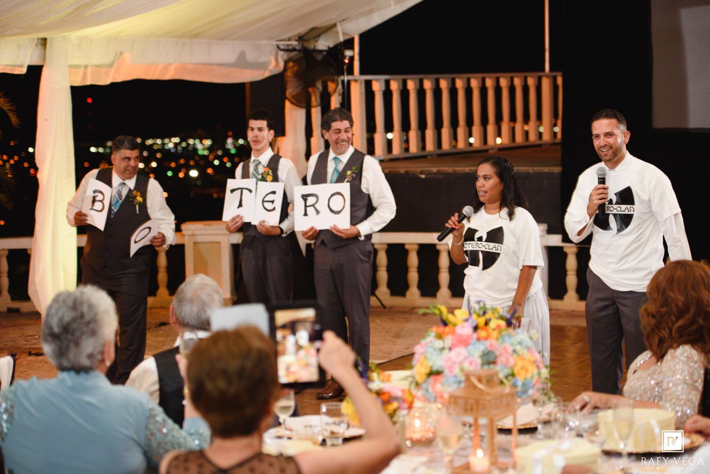 Groomsmen holding letters spelling TERO during fun wedding reception entertainment performance.