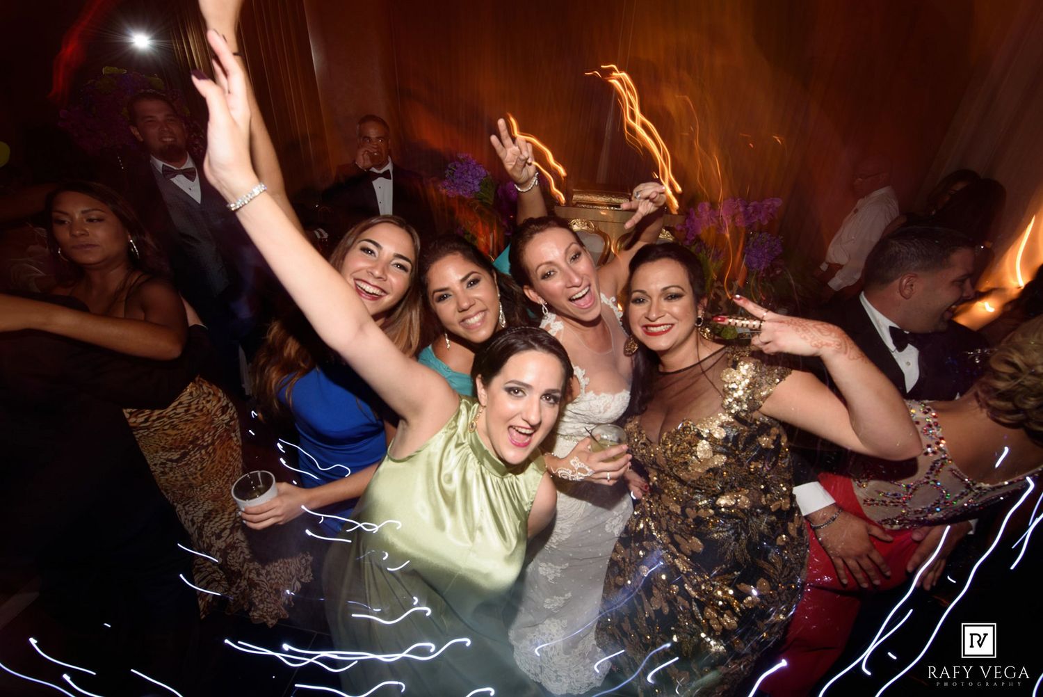 Five women in elegant attire celebrate joyfully at a glamorous evening party event.