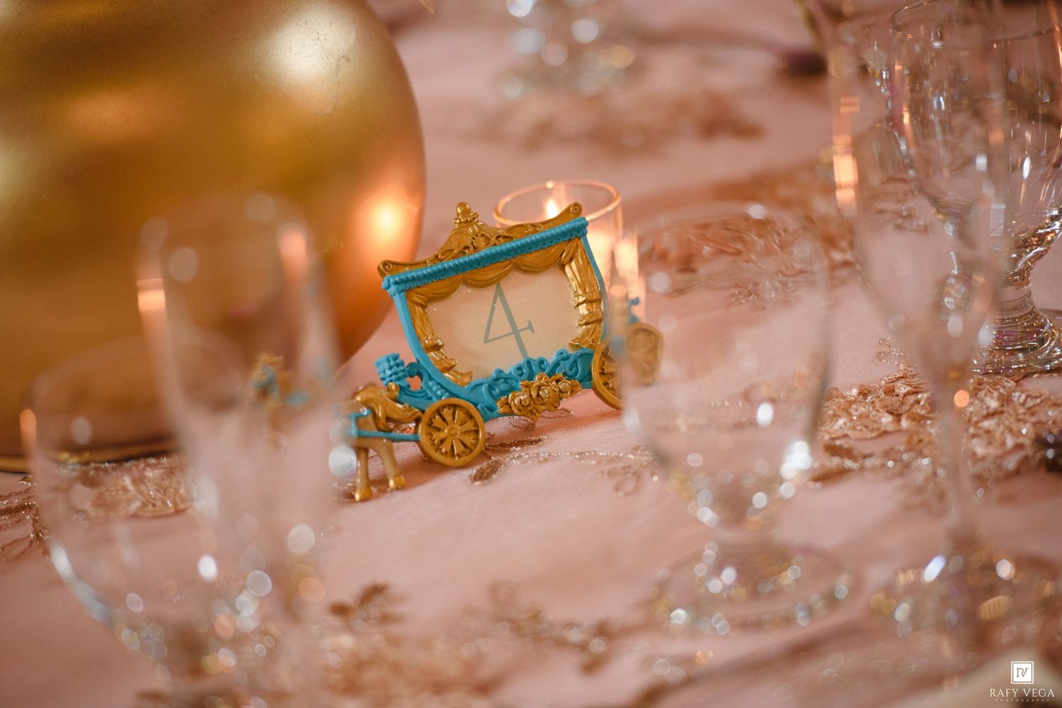 Elegant Cinderella carriage table number decoration on wedding reception table with crystal glassware.