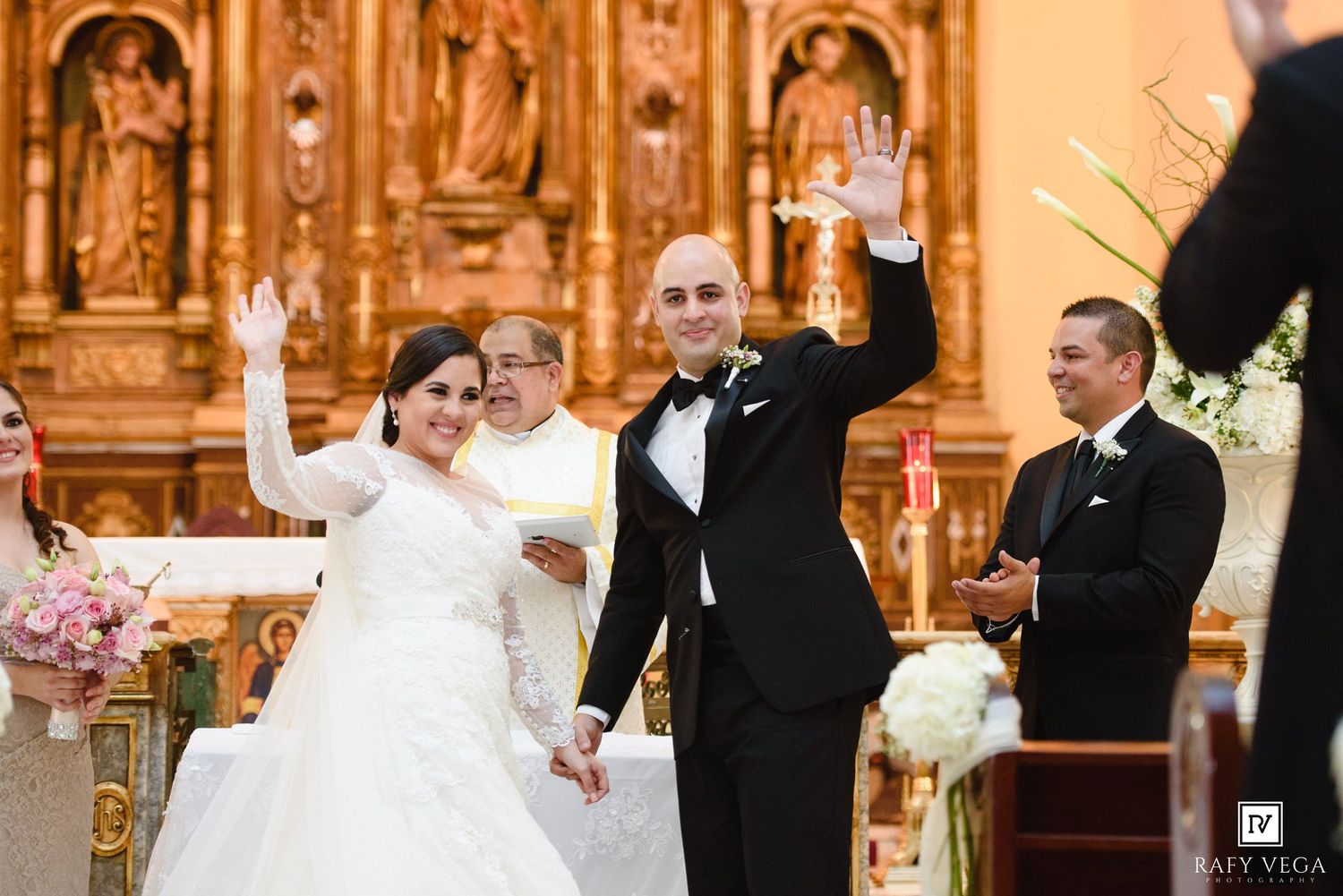 Bride and groom joyfully raise their hands at the altar during their church wedding ceremony.