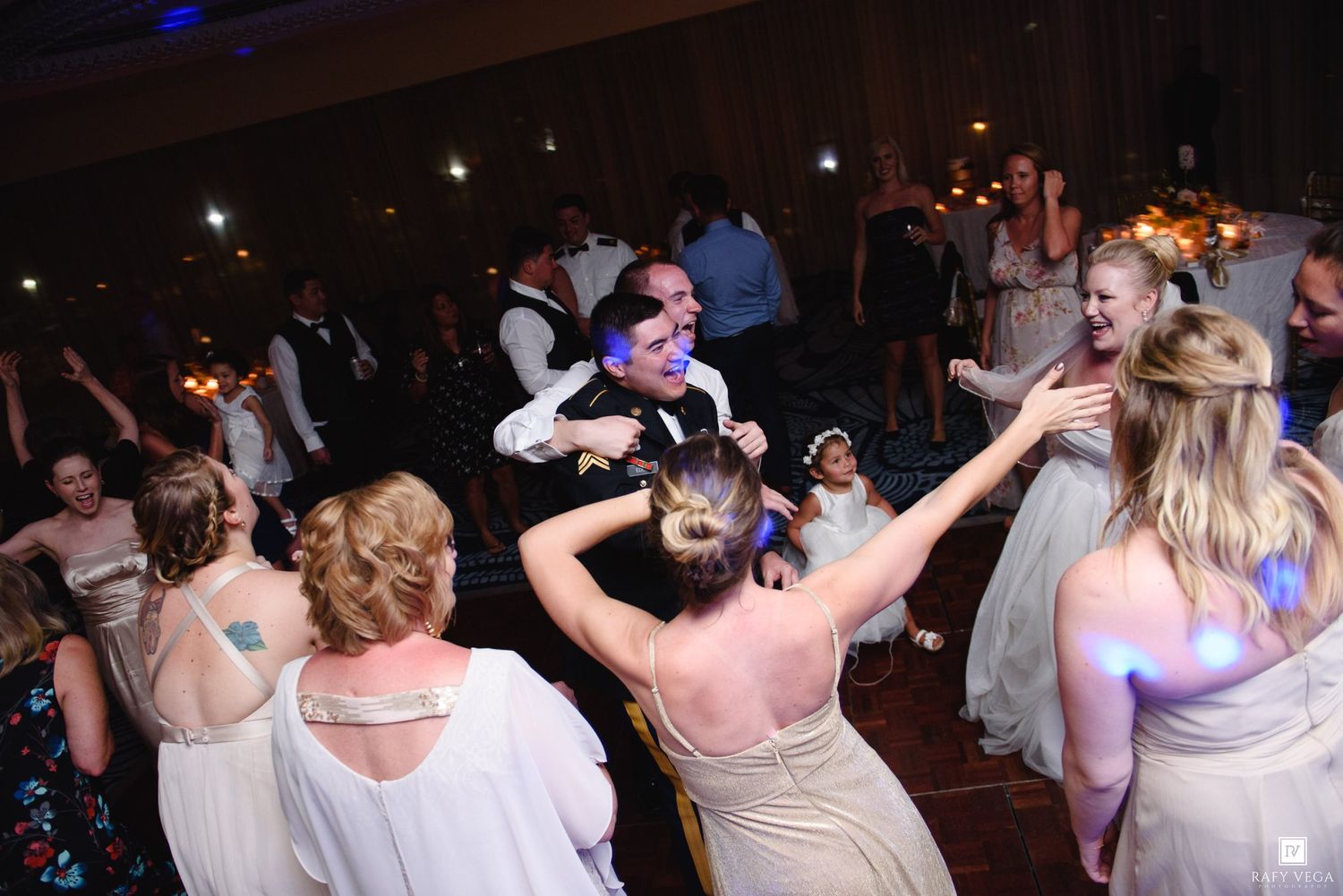 Guests dancing energetically at a lively wedding reception on a crowded dance floor.