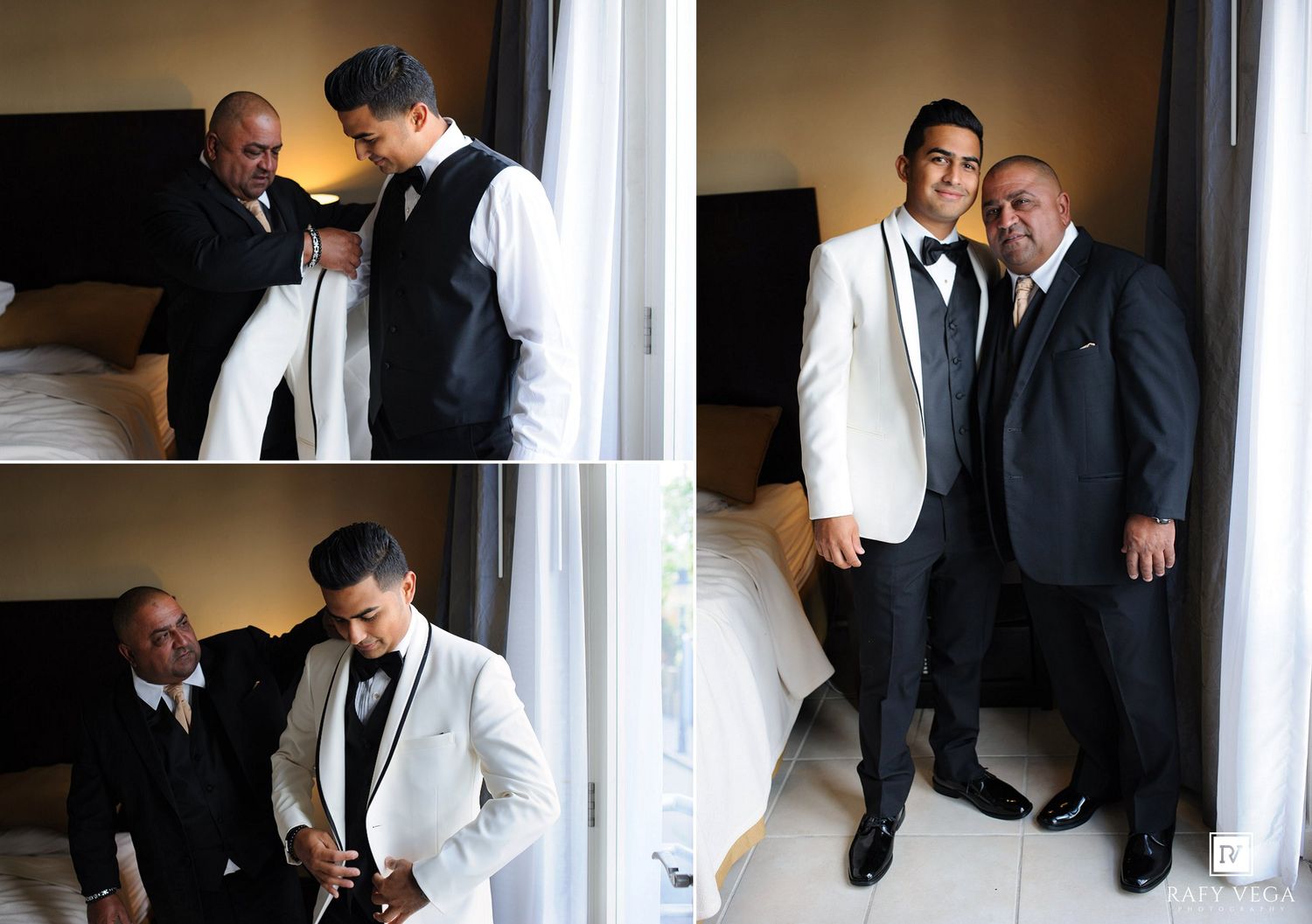 Two men in formal black and white tuxedos pose together in a bright bedroom, one helping the other dress for a special occasion.