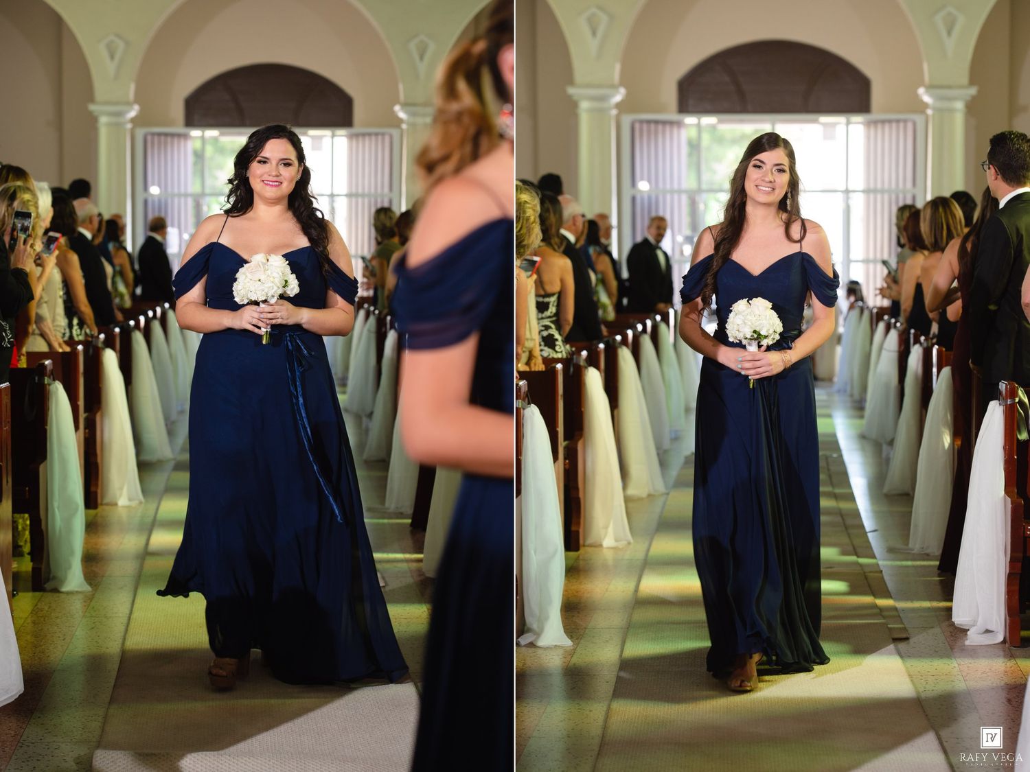 Bridesmaid in navy blue off-shoulder gown walks down church aisle holding white bouquet during wedding ceremony.
