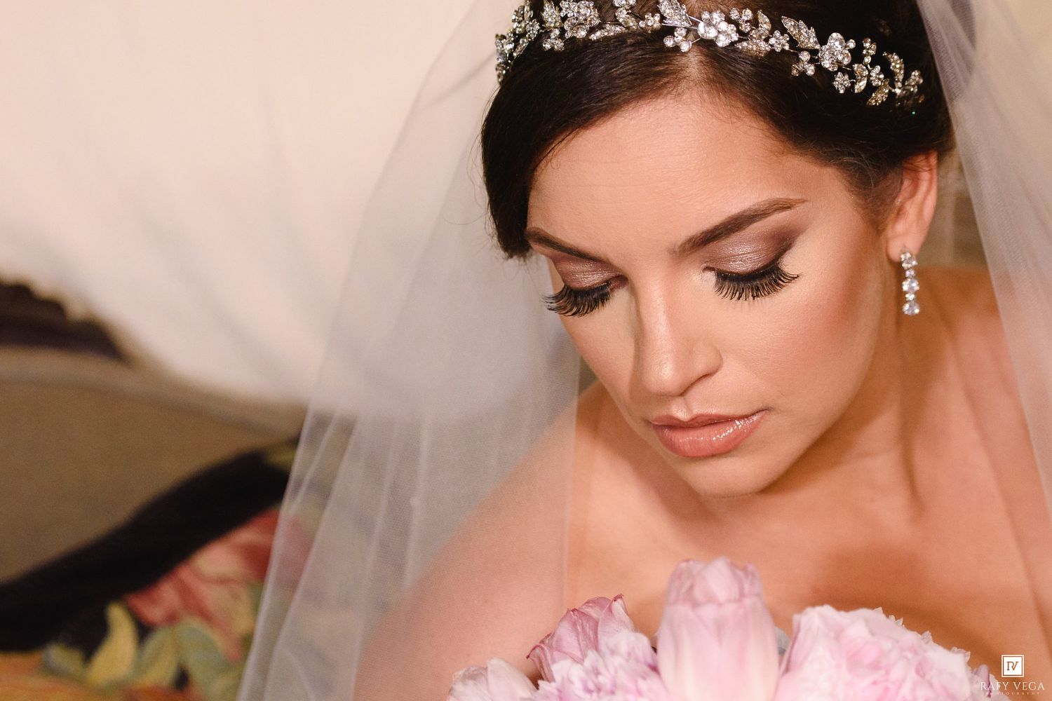 A beautiful bride wearing a crystal tiara and veil with elegant makeup on her wedding day.
