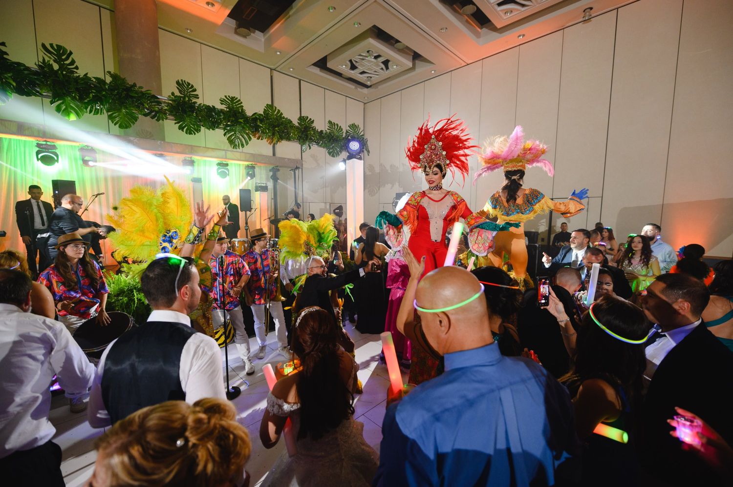 Colorful carnival performer in feathered costume entertains guests at a lively indoor celebration event.