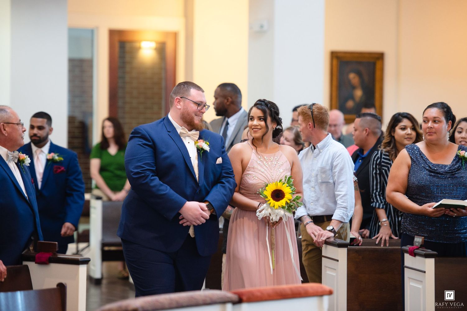 Bride and groom share a joyful moment at the wedding altar as guests look on in a sunlit church.
