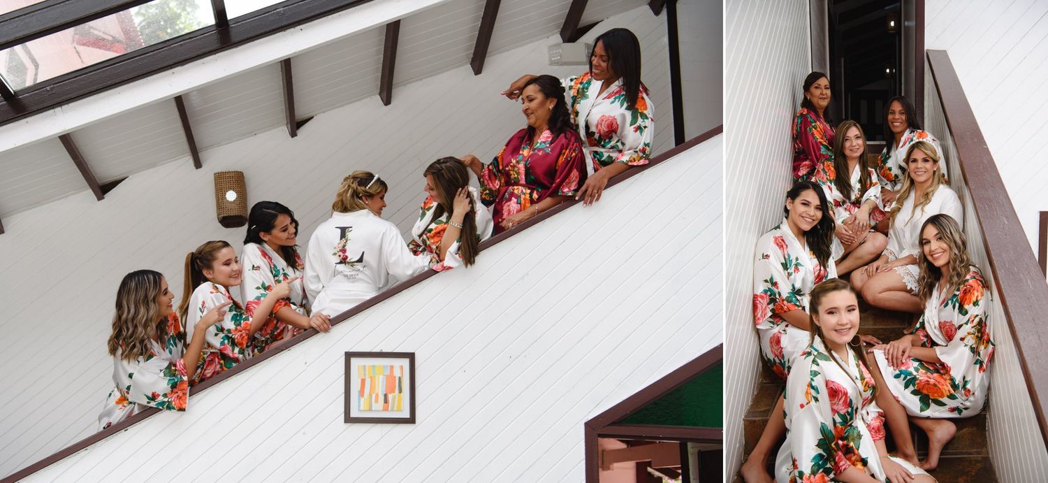 Bridesmaids in floral robes pose on a staircase during wedding preparations.