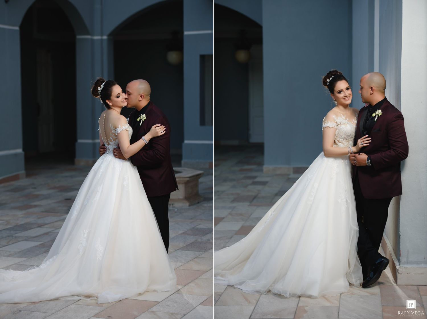 Bride and groom share romantic wedding portraits against a blue building, groom in burgundy suit.