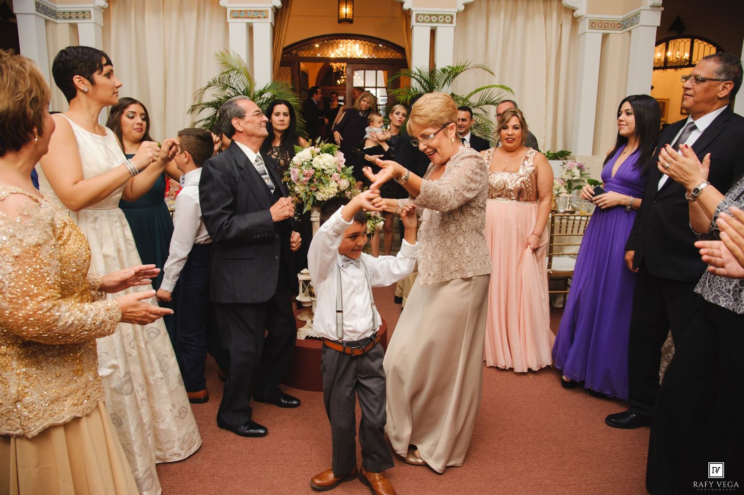 Guests dancing and celebrating at elegant wedding reception with bride holding bouquet.