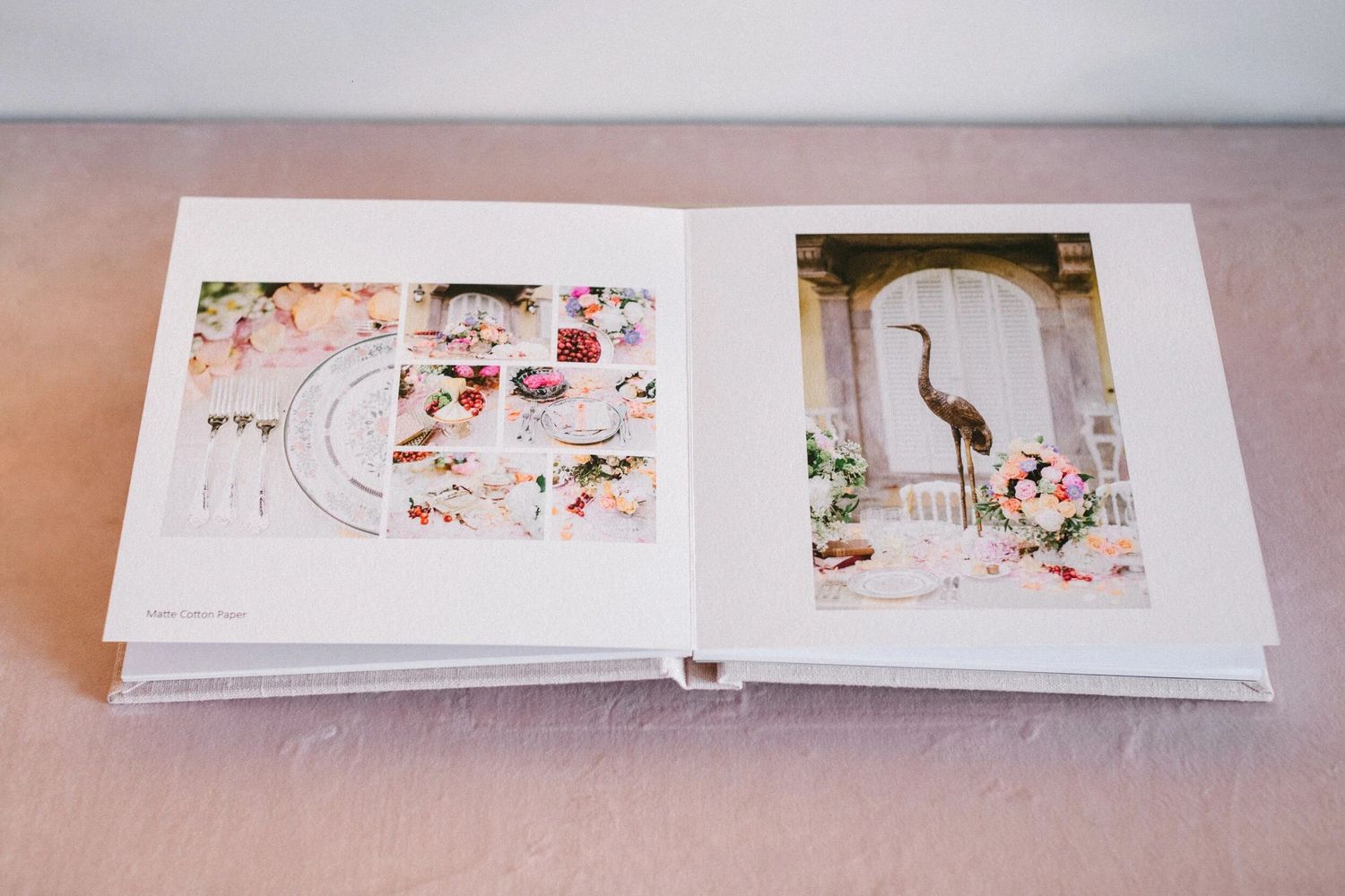 Open wedding photo album displaying floral reception details and an elegant heron statue surrounded by pink flowers.