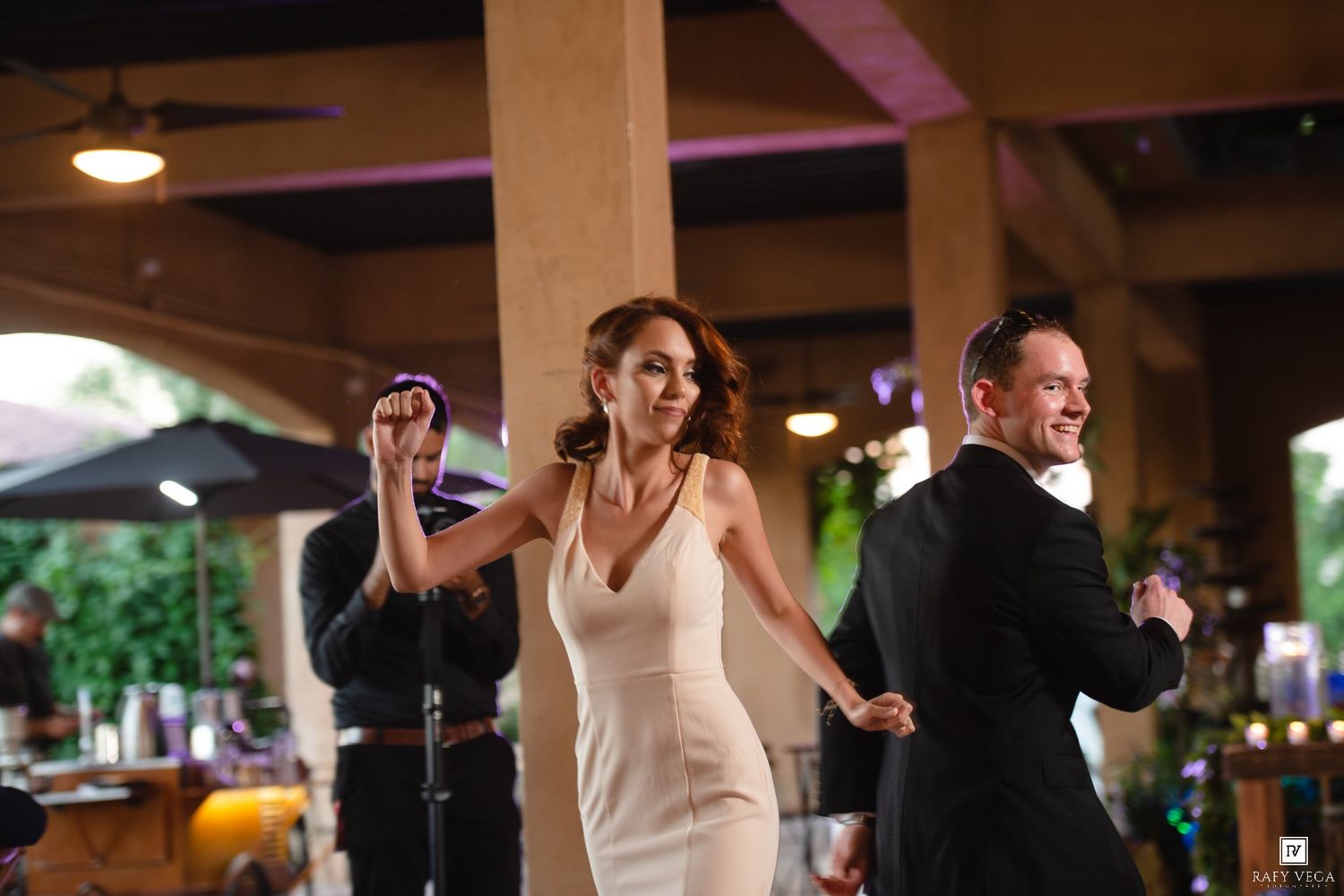 Bride in white dress and groom share first dance at elegant indoor wedding reception venue.