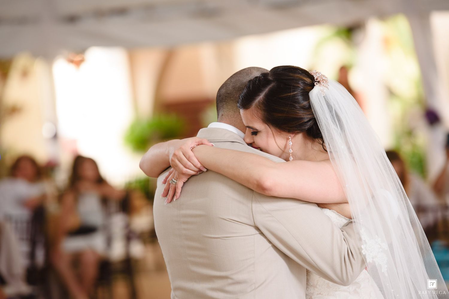 Bride and groom share intimate first dance embrace at elegant outdoor wedding ceremony.