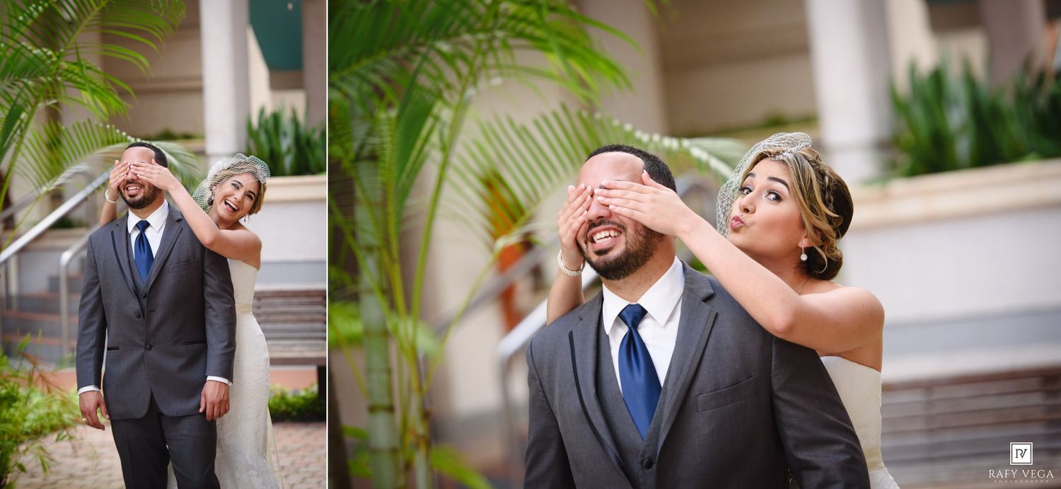 Bride surprises groom covering his eyes for first look moment outdoors at wedding venue.