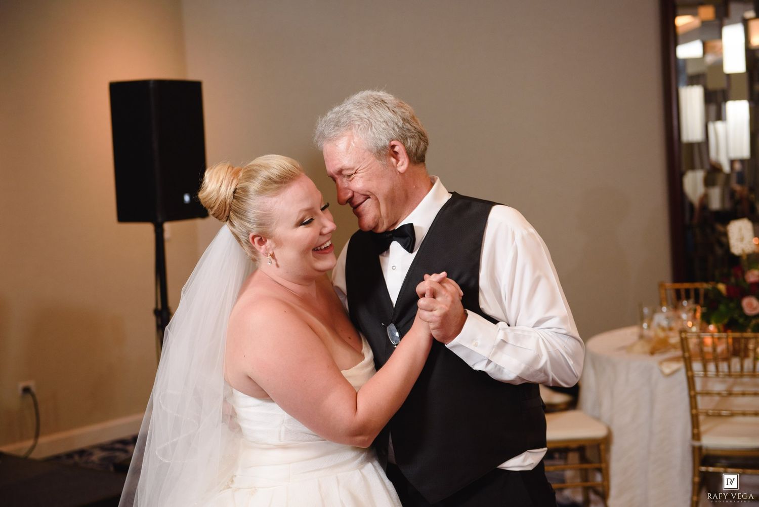 Bride and older gentleman share a joyful father-daughter dance at wedding.