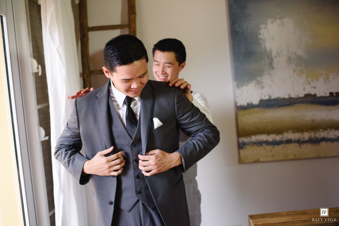 Two grooms in gray suits share a joyful moment together on their wedding day.