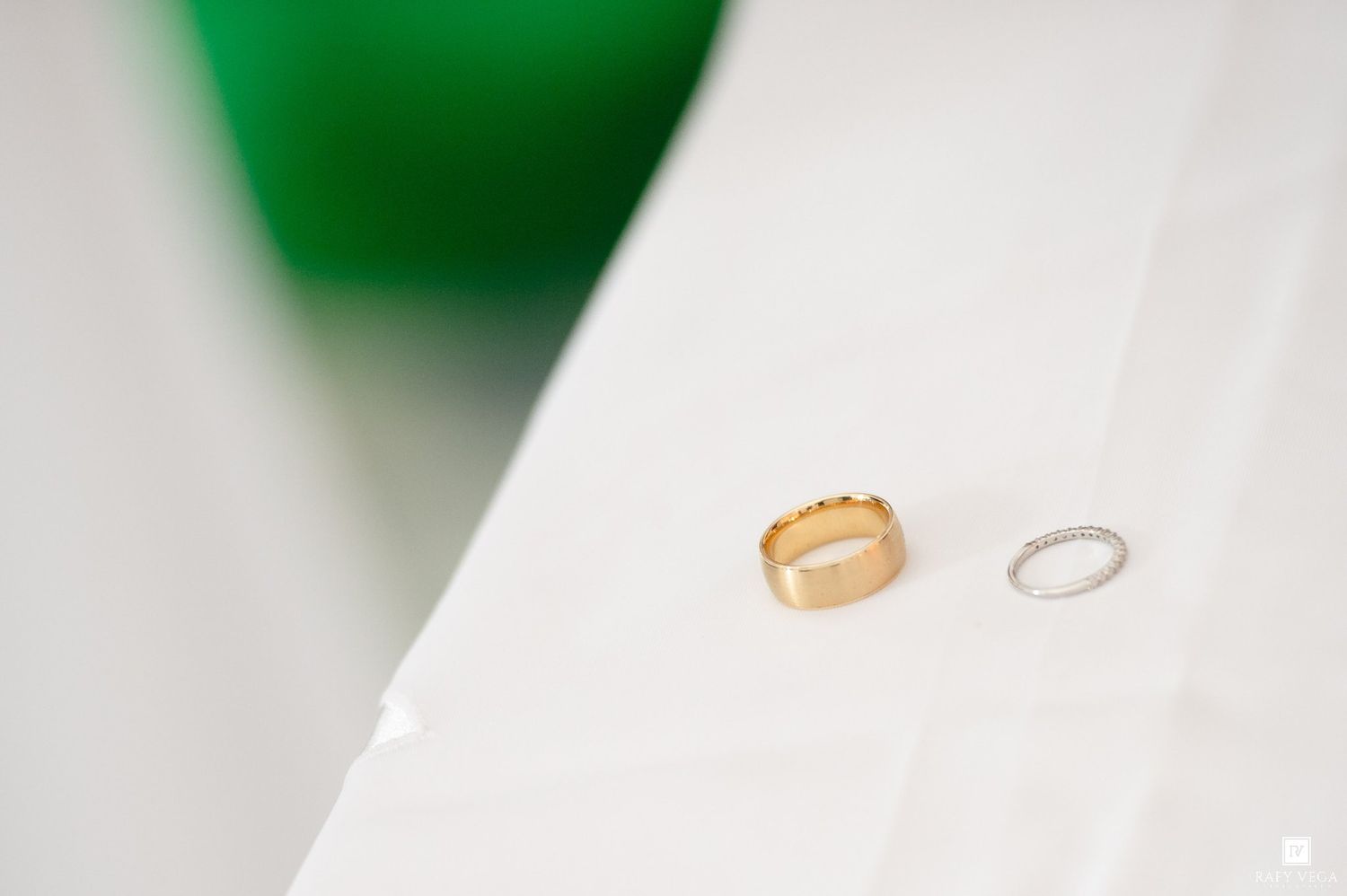 Two wedding rings, one gold band and one silver, placed on a white surface.