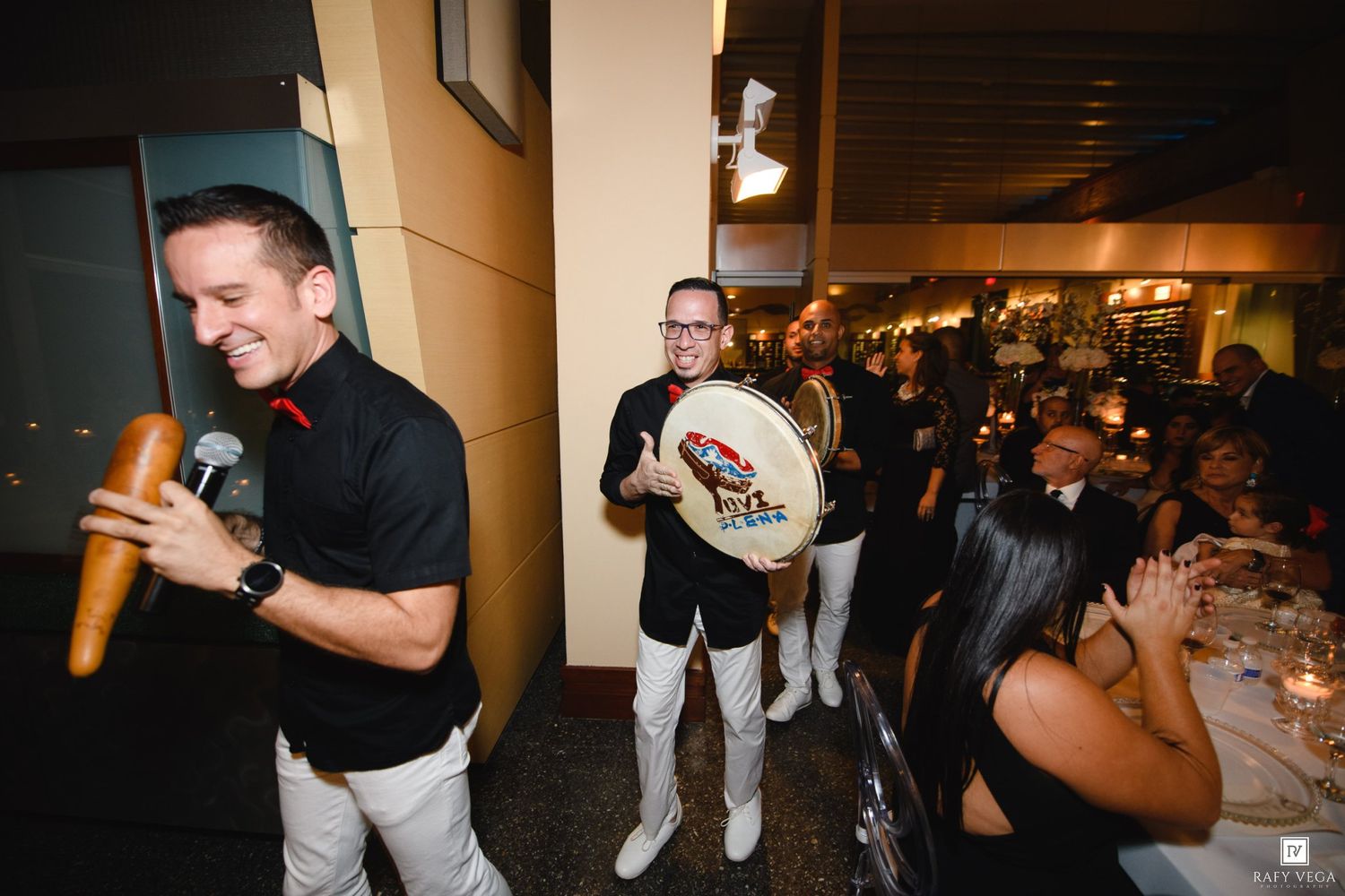 Live wedding band performers entertain guests with maracas and tambourine at festive reception dinner.