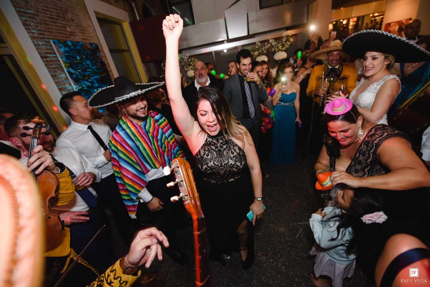 Guests dancing at a festive Mexican-themed party with sombreros, colorful serapes, and lively celebration atmosphere.